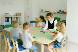 kids sitting on table cutting colored papers