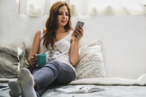 woman holding cup wearing tank top sitting on bed